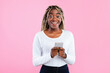 © Prostock-studio - People And Technology Concept. Portrait of excited smiling young black woman using smartphone standing isolated on pink studio background, looking at camera. Lady chatting online, typing sms