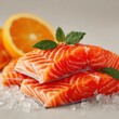 Three vibrant salmon fillets rest on a bed of crushed ice, accented with fresh mint leaves and slices of orange. The setup highlights freshness and culinary creativity, ideal for a seafood dish.