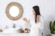 © Pixel-Shot - Beautiful young woman applying coconut oil onto hair in bathroom