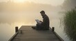 © aritha - Man working on digital tablet by a misty lake