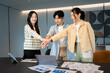 © Jestercine - Three asian coworkers putting hands together in front of a laptop, symbolizing motivation, unity, and team spirit during a successful meeting focused on building strong team spirit and collaboration