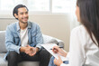 © KMPZZZ - Psychology, depression. Happy smile asian young man patient mental therapy explain symptom with psychologist while doctor woman taking notes at clinic. Psychologist with sick mental health person.