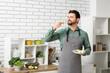 © Pixel-Shot - Handsome man eating toast with avocado in kitchen