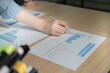 © wichayada - Accounting Analysis. Professional hand reviewing financial graphs and data on documents.