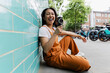 © Westend61 - Laughing person filming with vintage camera by turquoise wall outdoors