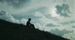 © THESUN - Person sits on grassy hilltop under cloudy sky feeling calm
