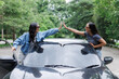 © crizzystudio - Two happy women giving high five celebrating road trip near car