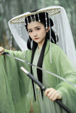 Young Asian woman in green attire holding a sword Chinese word means sword.