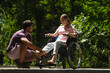 © kinomaster - Man Assisting Woman in Wheelchair in a Peaceful Park