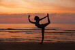 © Dina - silhouette of young woman on the beach at sunrise, doing yoga, standing in meditation position, doing breathing and balance exercise. Healthy lifestyle.