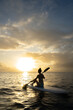 © Groovy Banana - Silhouetted woman in swimwear sitting on a paddleboard during sunset. Calm ocean, warm colors, and peaceful evening atmosphere. Outdoor summer lifestyle.
