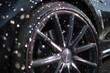 © PhotoProd - Water droplets cascade over a sleek car wheel being cleaned at a wash station under the bright sunlight