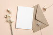 © nikavera - Blank white invitation or greeting card mockup with brown envelope and dried flowers, copy space for card designs presentation