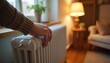 © Vadym - Hand touching radiator in cozy, warmly lit room. Interior home warmth comfort focus. Heating temperature control, relaxation lifestyle. Soft inviting homelike atmosphere, energy efficiency.