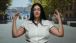© Krakenimages.com - Curvy woman in white uniform stands outdoors on city street gesturing with both hands in thoughtful expression under sunny clear sky.