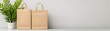 © STOCKJN - Two eco-friendly shopping bags are positioned next to a potted plant on a minimalist table against a neutral wall, creating a stylish and serene atmosphere.