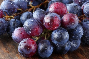 Wall Mural - Freshly harvested grapes glistening with moisture on a rustic wooden surface in natural lighting