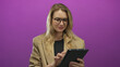 © Krakenimages.com - Blonde woman using tablet on pink background, dressed in beige blazer, showcasing technology and modern communication.