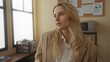 © Krakenimages.com - Woman talking in bright modern office workspace dressed in professional attire with natural light enhancing her focused expression seated by a window with a corkboard background