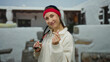 © Krakenimages.com - Young woman with racquet and red headband making a heart hand gesture on an outdoor city street backdrop exuding charm