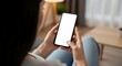 © National Star - Woman holding a smartphone with a blank white screen in a cozy living room setting indoors at daytime on transparent background