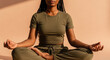 © Bakha - peaceful young woman practicing mindfulness meditation in lotus position with closed eyes and relaxed expression on soft beige background calm self care indoor wellness