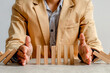 © Queenmoonlite Studio - Businessman Uses Both Hands To Stop Falling Dominoes