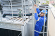 © DG PhotoStock - Technician climbs rooftop to fix HVAC and ventilation systems on a tall building.