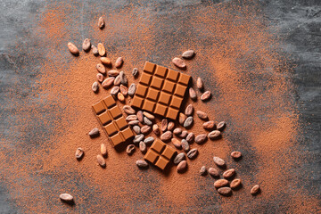 Wall Mural - Sweet chocolate with cocoa beans and powder on dark background