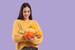 © Pixel-Shot - Beautiful young happy woman with many pumpkins on purple background