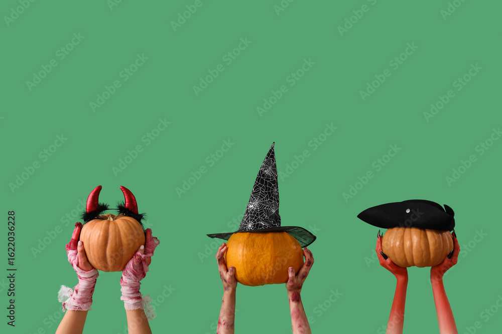 Mummy, zombie and devil hands holding pumpkins with Halloween headband on green background