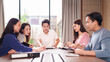 © Pichsakul - Asian business professionals discuss projects collaborate strategy analyze data working together sharing ideas planning future initiatives modern office meeting room environment