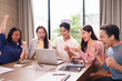 © Pichsakul - Asian adult professionals celebrating project success reviewing data team meeting modern office