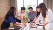 © Pichsakul - Asian adult professionals brainstorming project strategy corporate office discussing documents analyzing data developing innovative solutions together