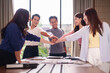 © Pichsakul - Young adult Asian business professionals demonstrating teamwork unity collaboration success at bright modern corporate office meeting