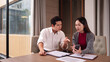 © Pichsakul - Asian business professionals collaboratively discuss strategies using smartphone and documents in a modern office meeting room