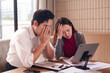 © Pichsakul - Asian business couple facing financial stress reviewing documents in office struggling with complex data analysis and challenging market conditions