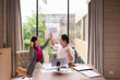 © Pichsakul - Asian coworkers high five celebration successful project completion modern office environment business triumph partnership