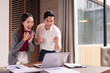 © Pichsakul - Asian business professionals celebrate project success viewing laptop data charts in modern office boardroom setting