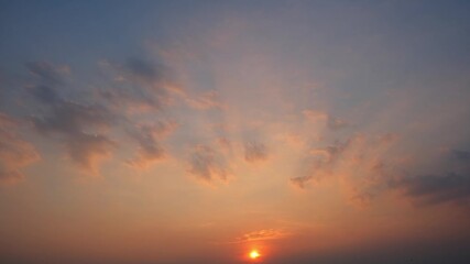 Wall Mural - a timelapse video shows a beautiful sunset sky with the glowing sun near the horizon, casting warm g