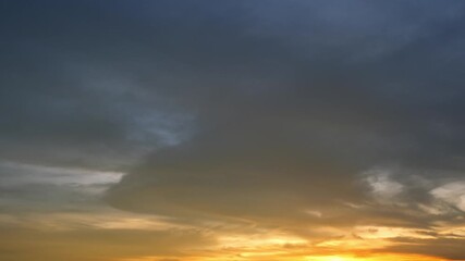 Wall Mural - A timelapse showcases a dramatic sunset sky with dense, dark clouds above glowing golden and orange hues near the horizon, capturing the intense and moody transition from day to night. Time-lapse.
