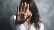 © Ketanoff - In a calm indoor environment, a woman raises her hand to signal stop as she addresses harassment, visibly expressing defiance and courage against inappropriate behavior