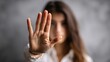 © Ketanoff - In a calm indoor environment, a woman raises her hand to signal stop as she addresses harassment, visibly expressing defiance and courage against inappropriate behavior