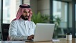 © Valentina - Arab Saudi man in office working in business corporate background using laptop or phone in a meeting.