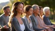 © Puhnnawit - A serene, natural group meditation session with a diverse group of people sitting cross-legged in warm morning sunlight.