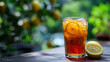 © Sadia - A glass of iced tea with lemon slices on a wooden table with a blurred green background of lemon trees