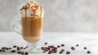 © AndyAziz - A delicious caramel latte topped with whipped cream and drizzled caramel sauce sits among scattered coffee beans.