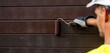 © ronstik - house painter with paint roller painting wooden exterior siding with protective color. wood protection. banner with copy space