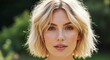 © Pratondo - Close-up portrait of a young woman with a stylish blonde bob haircut, outdoors in soft sunlight.
