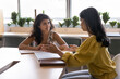 © fizkes - Two Indian women colleagues engaged in discussion during meeting in office, planning joint project, outlining tasks, timelines, and responsibilities, providing constructive feedback on work or ideas